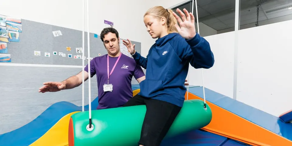 Therapist guiding a patient through a suspended sensory-gym exercise
