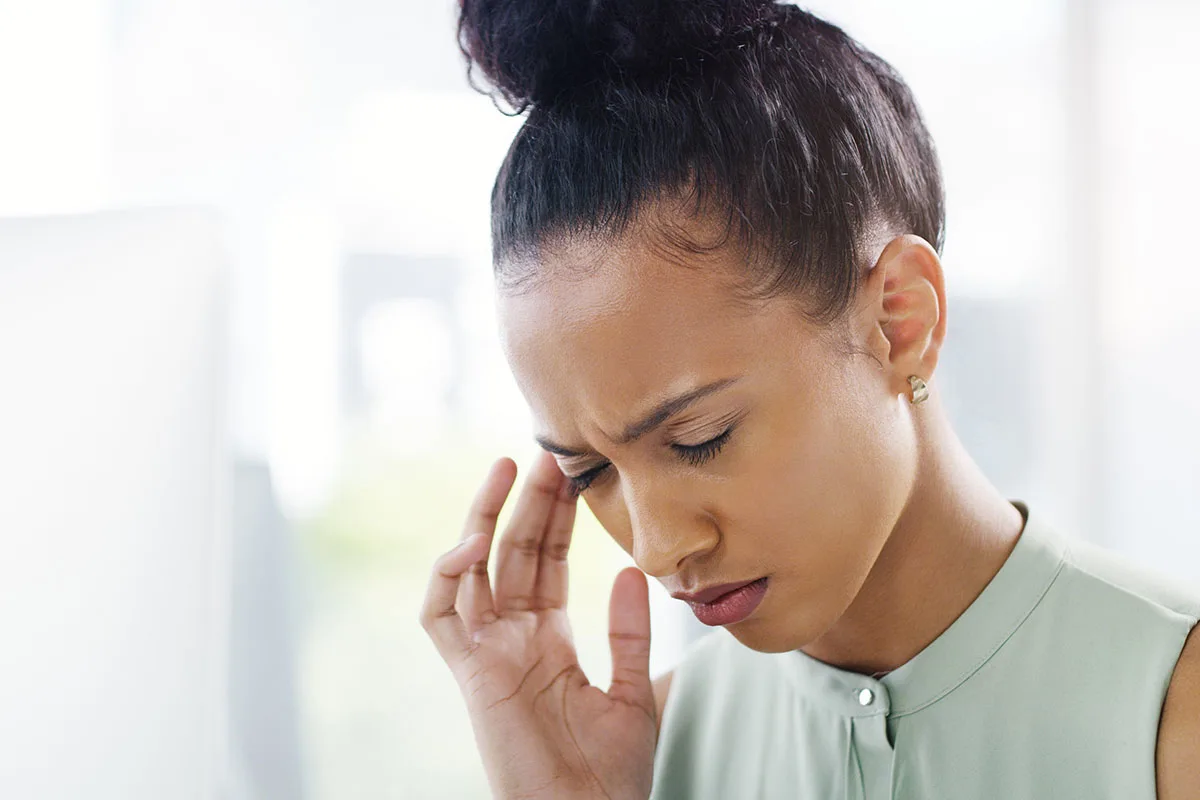 Woman holding her temple with a pained expression, a common post-concussion headache