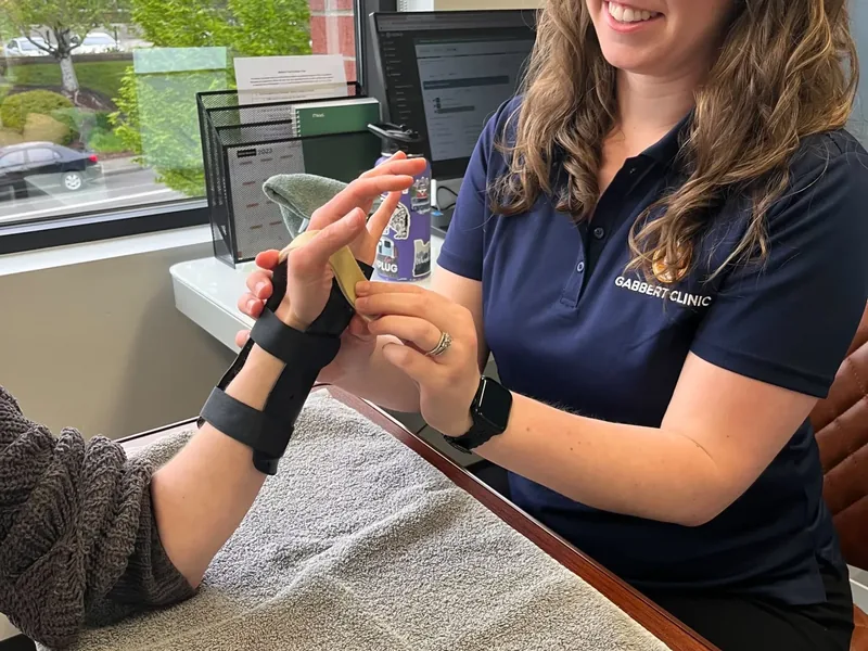 Hand therapist guiding a patient in a wrist splint through a finger exercise
