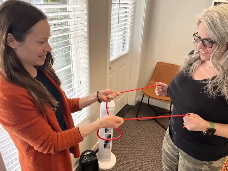 Occupational therapist guiding a patient through a two-handed resistance band exercise at Gabbert Clinic