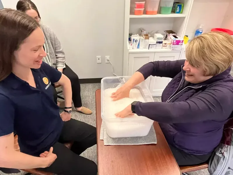 Certified hand therapist working with a patient during a warm paraffin hand treatment