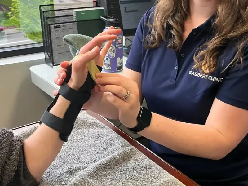 Therapist guiding active finger extension for a patient in a wrist splint