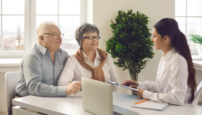 Clinician consulting with a patient and their spouse at a desk
