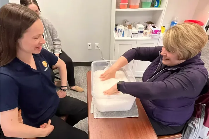 Certified hand therapist working with a patient during a warm paraffin hand treatment