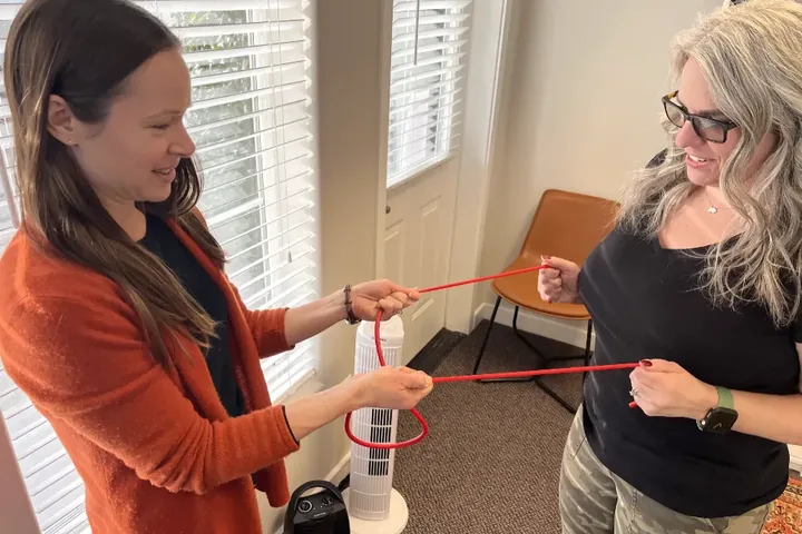 Therapist guiding a patient through a standing resistance band exercise