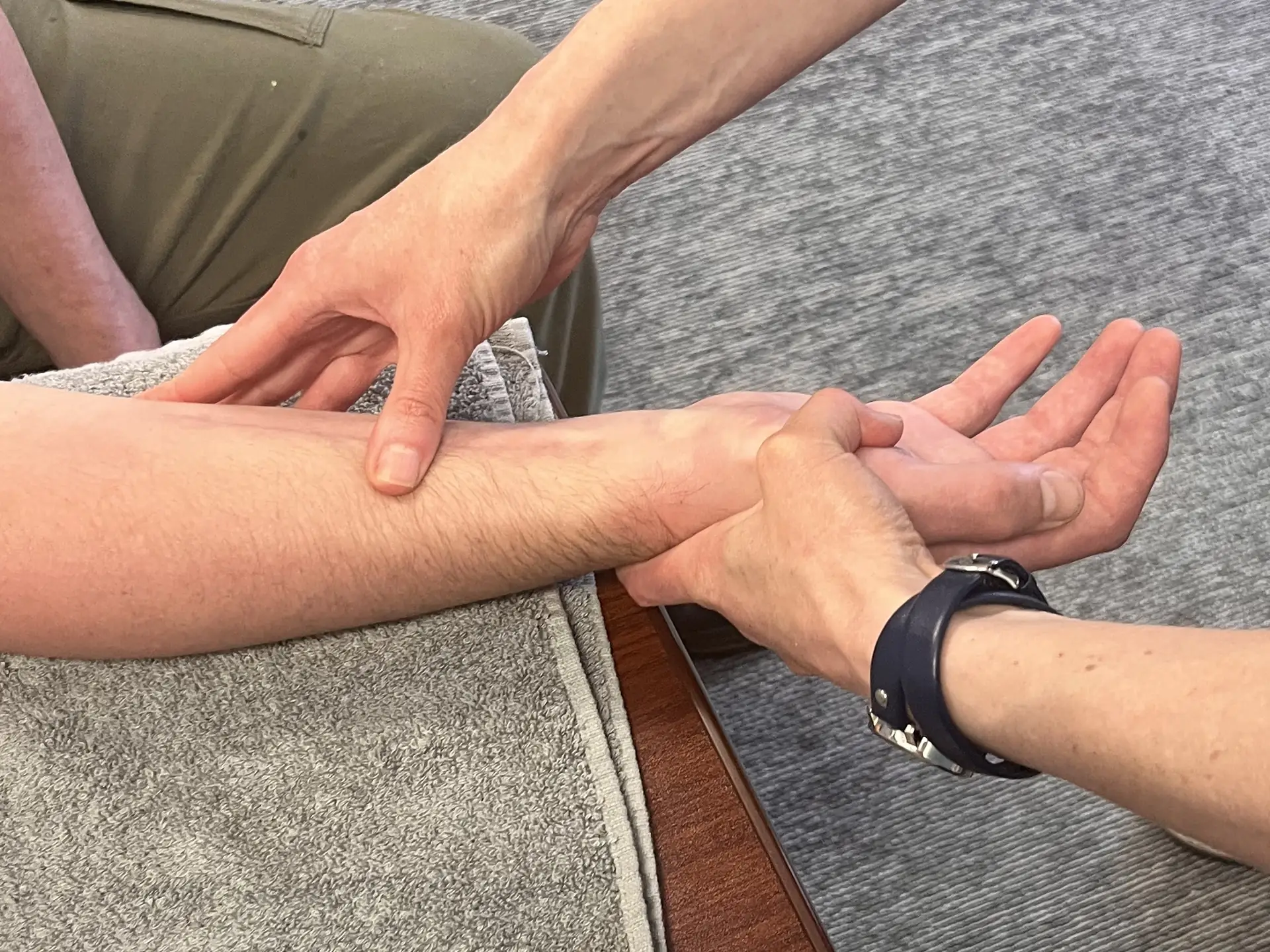 Close-up of a Gabbert Clinic hand therapist pressing along a patient's forearm while supporting the wrist and open hand