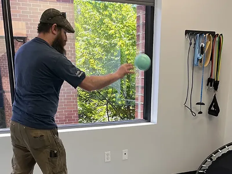 Patient working through a return-to-function ball drill in the therapy gym
