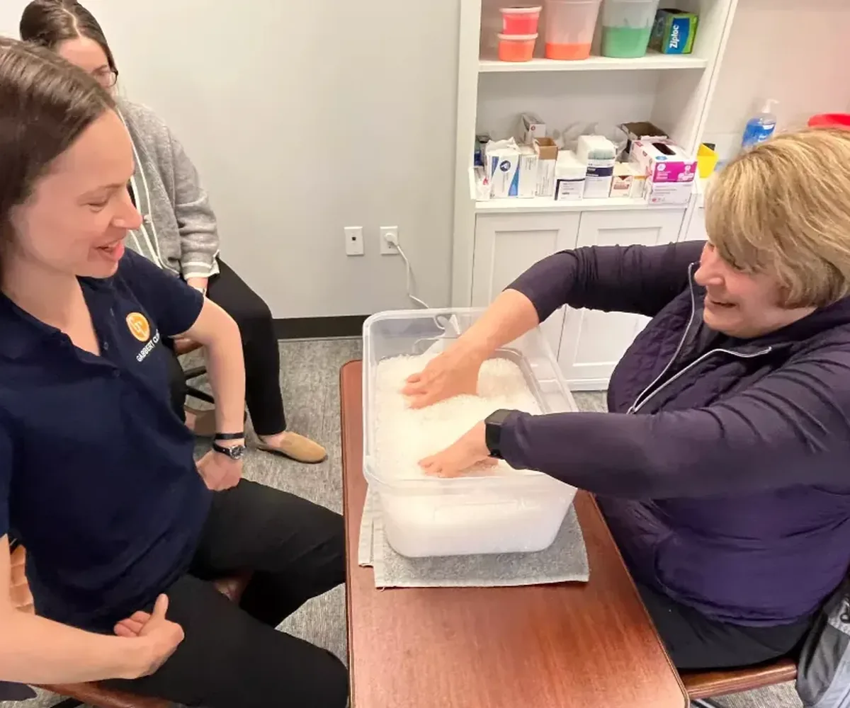 Certified hand therapist working with a patient during a warm paraffin hand treatment