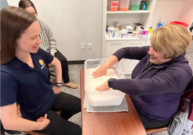 Certified hand therapist working with a patient during a warm paraffin treatment