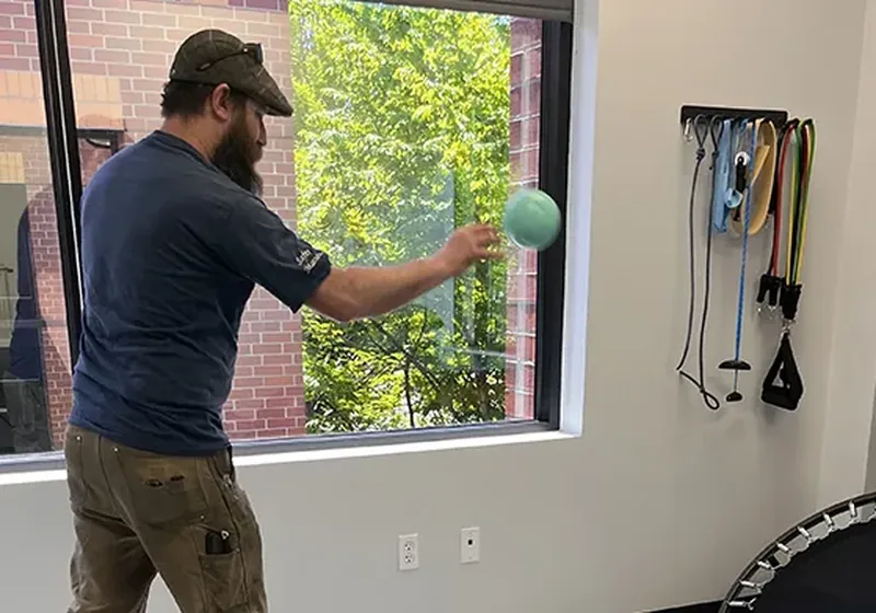 Patient working through a return-to-function ball drill in the therapy gym